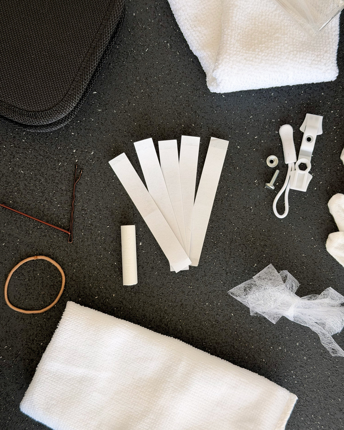 Close up of the bridal emergency kit, hair tie, bobby pins, hem tape strips and emergency zip