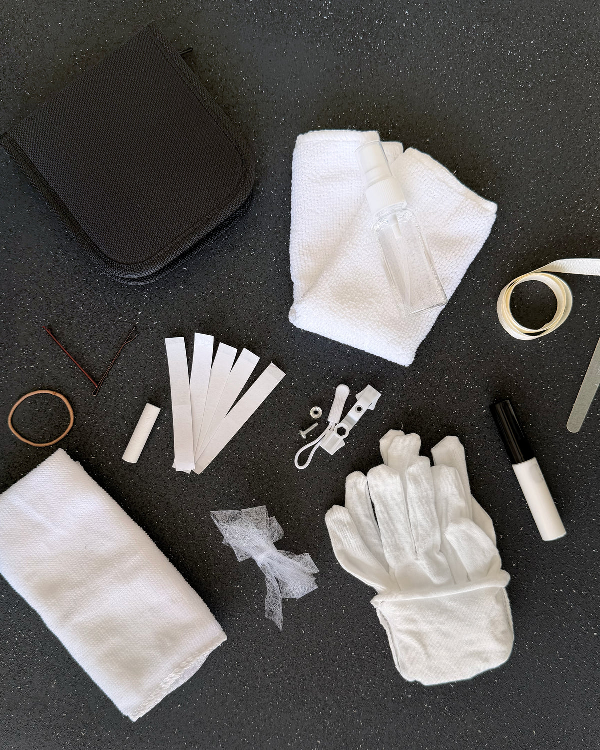 Bridal emergency kit contents laid out, cotton gloves, stain remover, sewing kit, hem tape, ribbon and flannel