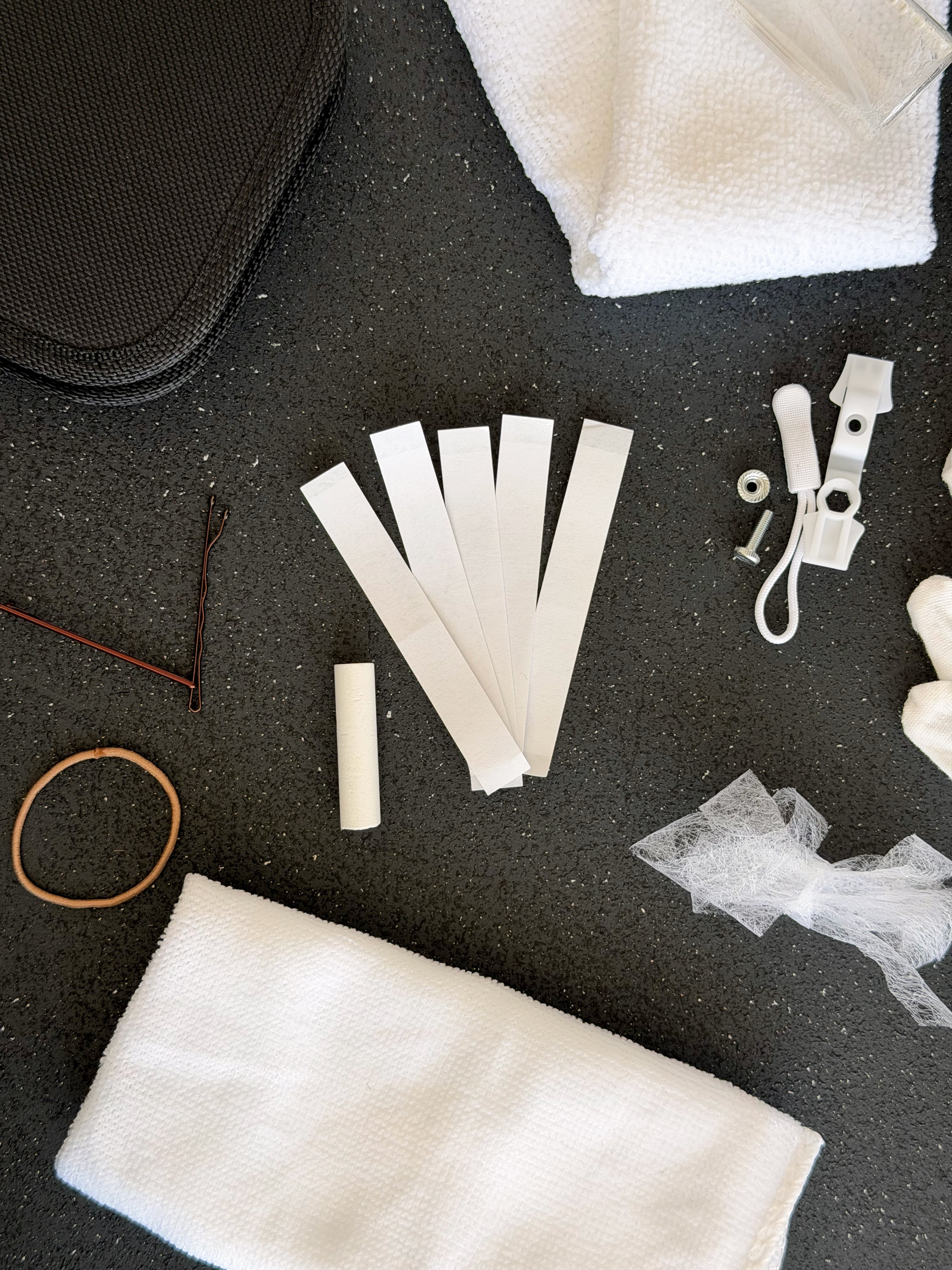 Close up of the bridal emergency kit, hair tie, bobby pins, hem tape strips and emergency zip