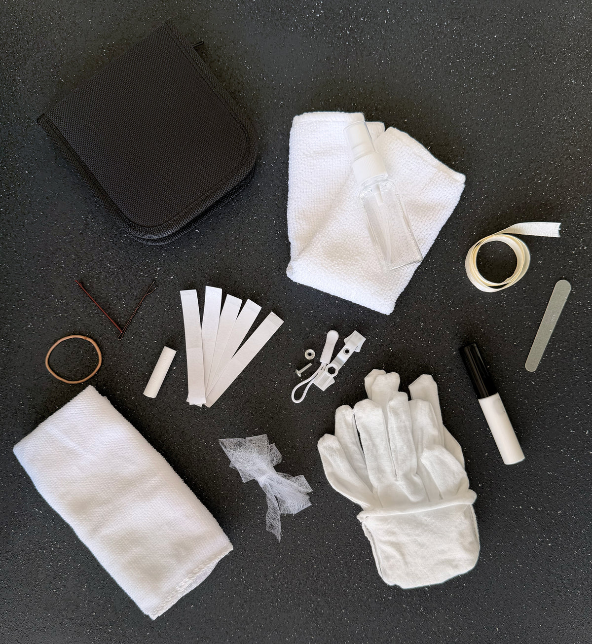 Bridal emergency kit contents laid out, cotton gloves, stain remover, sewing kit, hem tape, ribbon and flannel